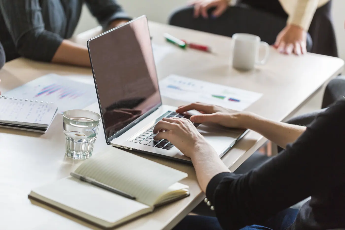 Aantekeningen, grafieken en een laptop op tafel tijdens een overleg