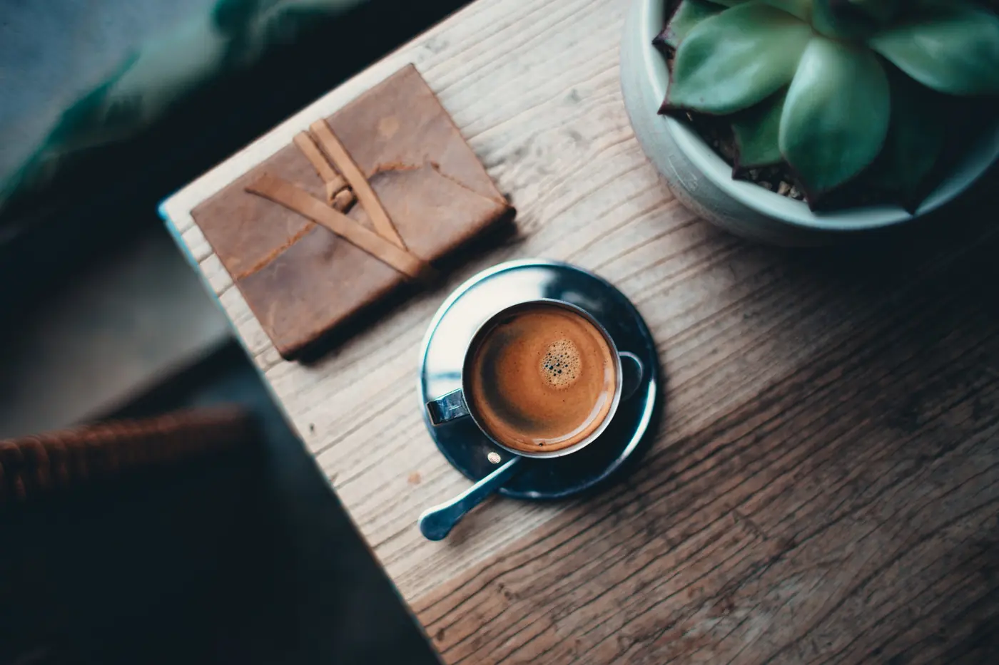 Kop koffie en een notitieboek op een houten tafel